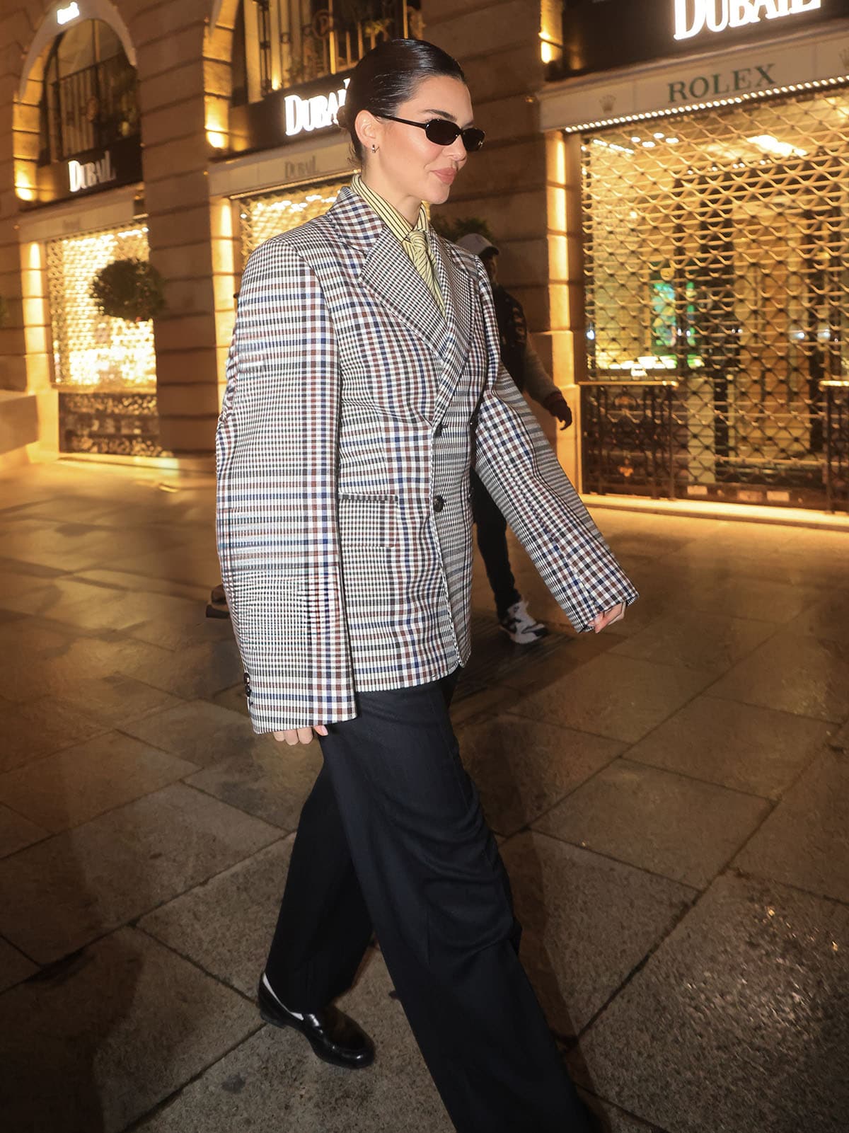 Kendall Jenner's chic business attire features an oversized Bottega Veneta Pre-Spring 2025 structured check cotton blazer, a yellow-striped collared shirt, and pinstripe trousers