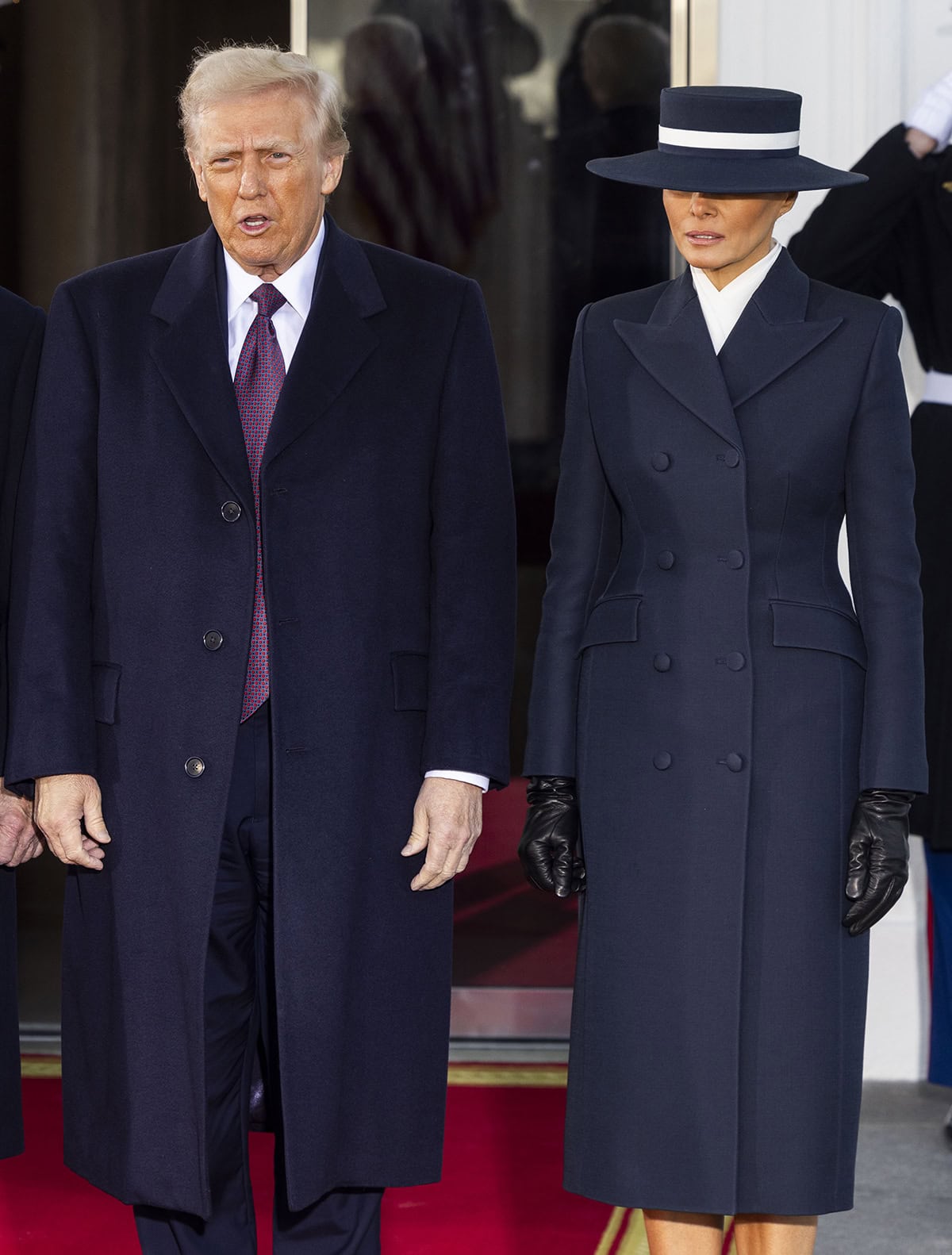 Melania Trump looks regal in a navy blue Adam Lippes double-breasted coat with a white wrap blouse underneath