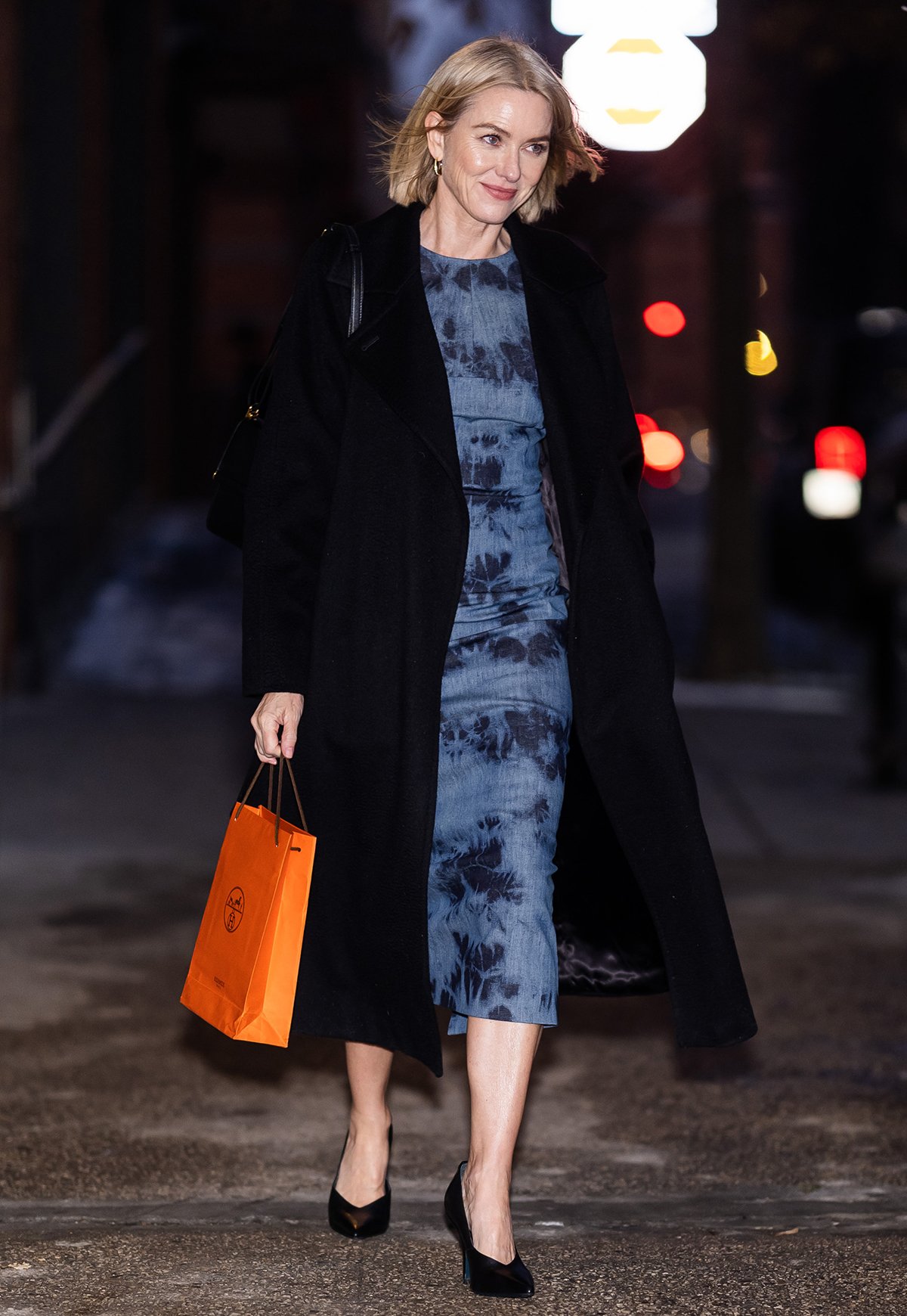 Naomi Watts teams her classic pumps with a patterned blue dress and a black coat