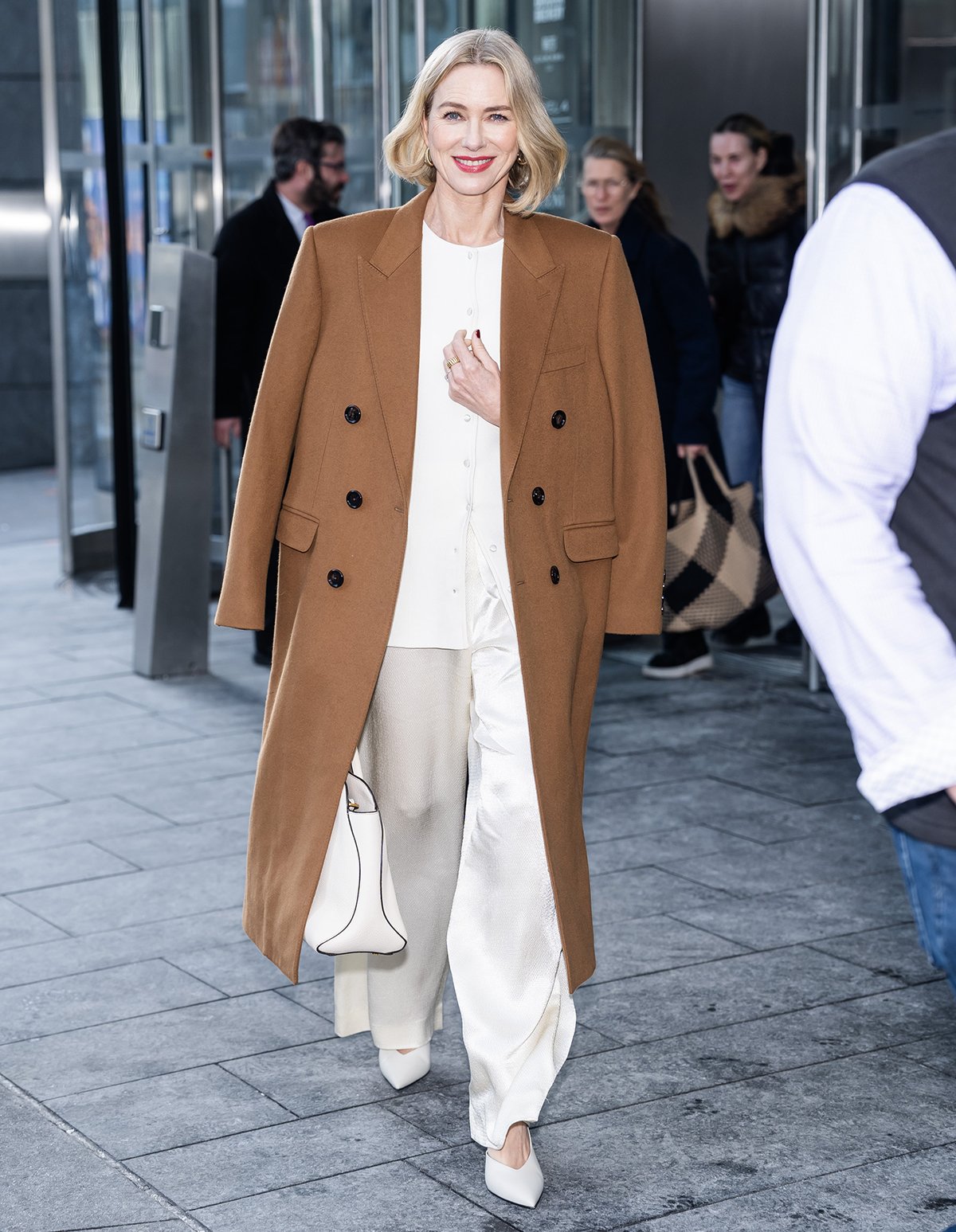 Naomi Watts opts for pure sophistication by teaming her pointy white pumps with an ivory Attersee The Compact knit top, matching airy silk pants, and a brown Celine coat