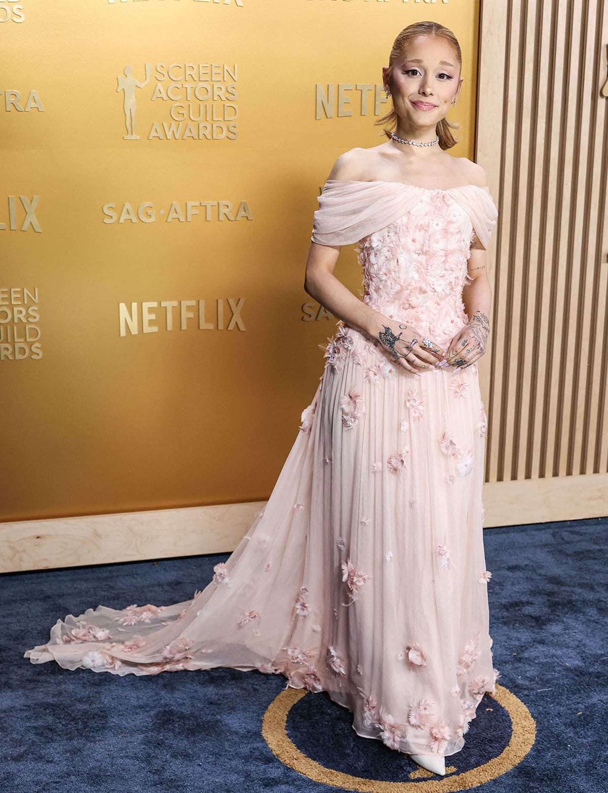 Ariana Grande looks dreamy in a pale pink tulle gown with draped off-the-shoulder sleeves and feathered flowers custom-made by Loewe creative director Jonathan Anderson