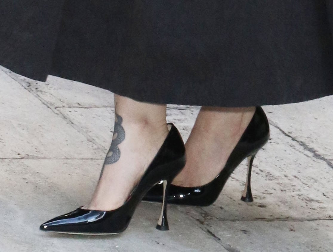 Dove Cameron displays her tattooed feet in a pair of black patent pointed-toe pumps with spool heels