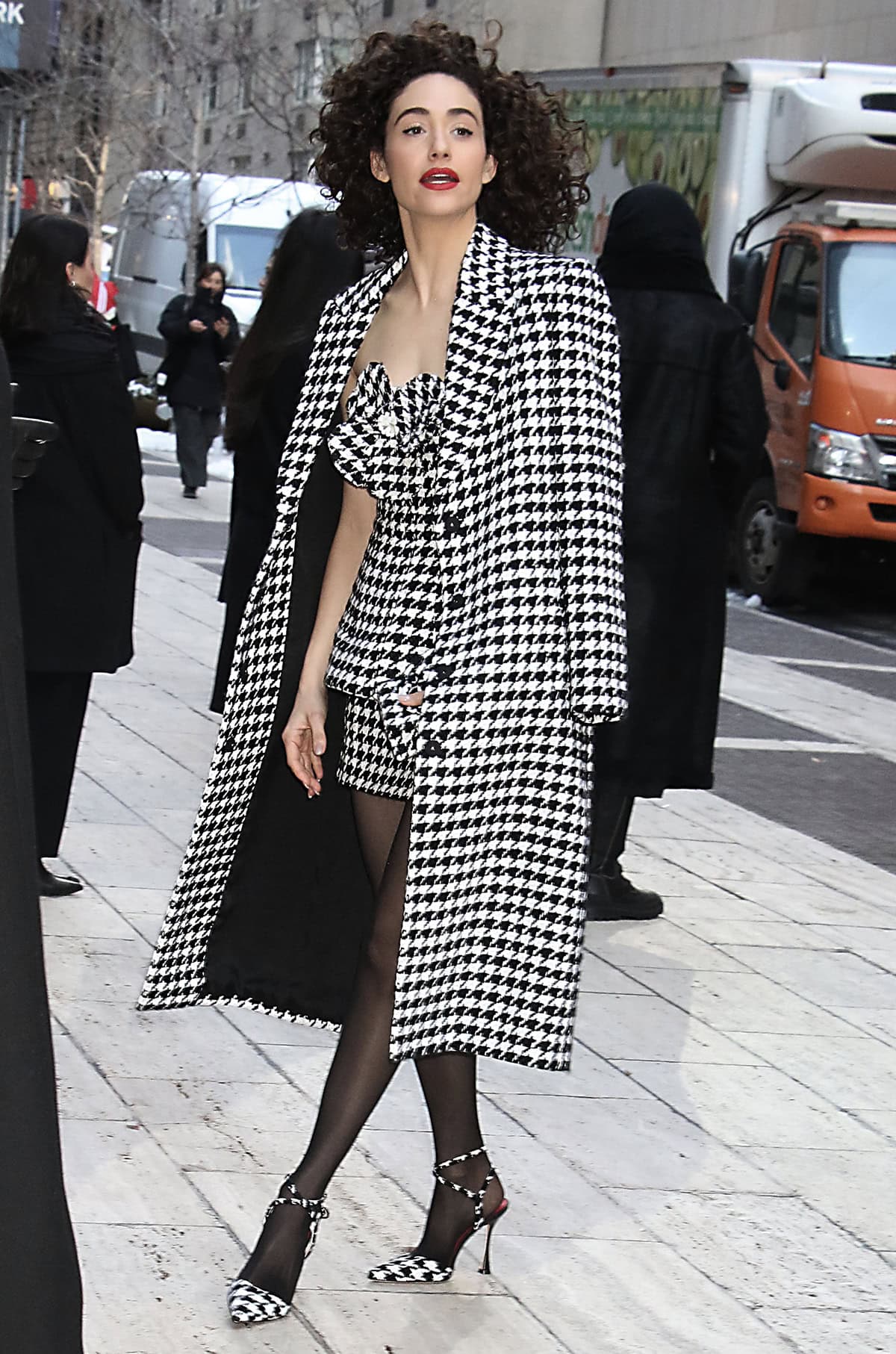 Emmy Rossum completes a head-to-toe houndstooth look with a coat and a strapless mini-dress featuring a 3D rosette and a peplum detail