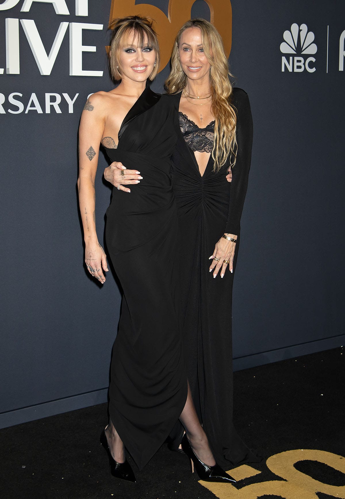 Miley Cyrus, with her mom Tish Cyrus, adopts an understated but chic and edgy look in an archival Jean Paul Gaultier one-shoulder tuxedo dress