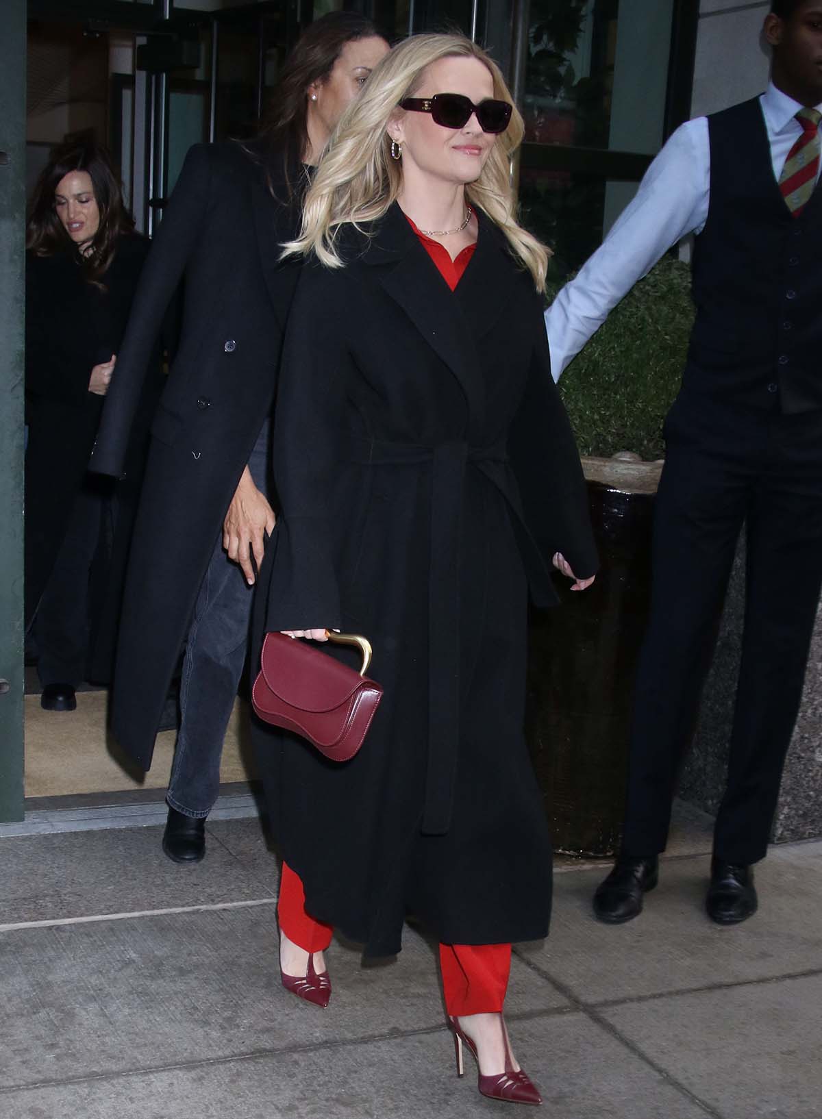 Reese Witherspoon dons a fiery red Lafayette 148 shirt and matching trousers with a black Max Mara coat as she exits The Kelly Clarkson Show studios