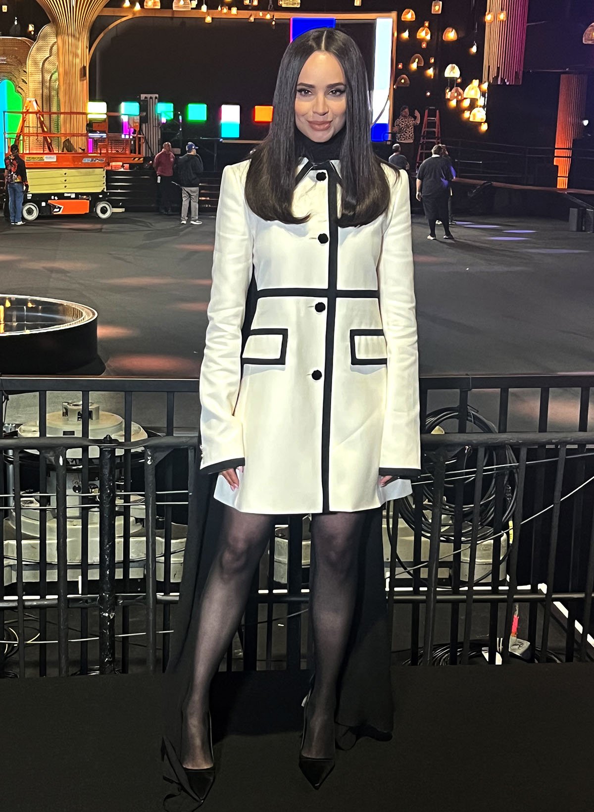 Sofia Carson looks stunning in a winter white Nina Ricci coat dress featuring black trims that give it a 1960s mod look