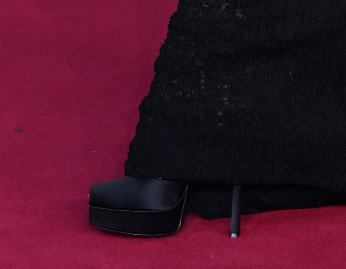 Zoe Saldana opts for the Saint Laurent La Scandale platform pumps in shiny black satin, adding edge and elegance to the look