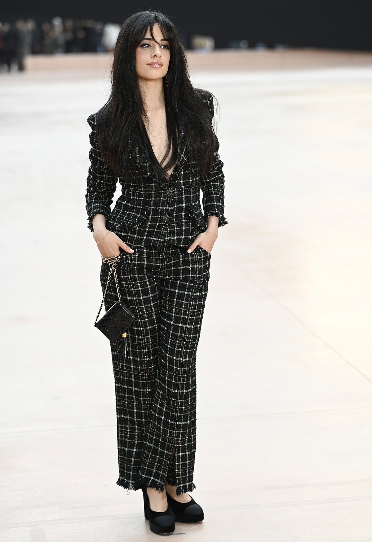 Camila Cabello teams her chic platform pumps with a checkered tweed suit featuring a daring plunging neckline and fringed trims