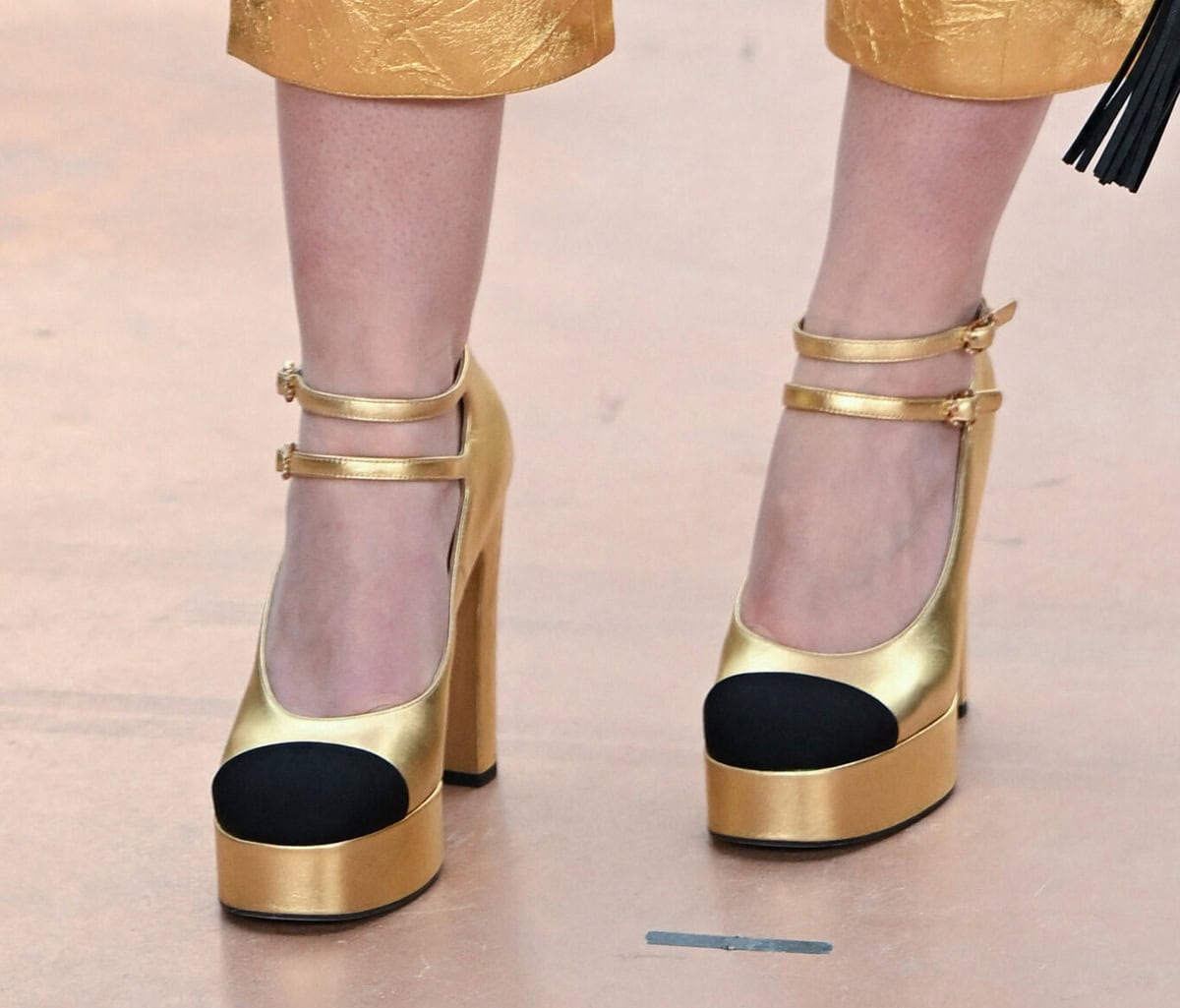 Dakota Fanning stands out in a pair of gold metallic platform pumps with black toe caps, platforms, and block heels