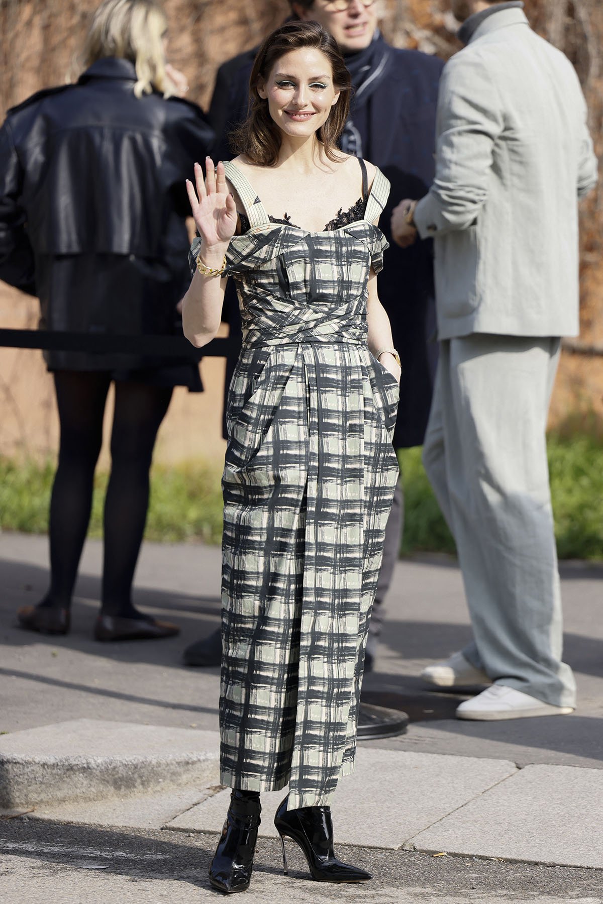 Olivia Palermo wears her Casadei Superblade Narcissist boots with a chic plaid dress featuring cold shoulders, thick shoulder straps, and a pleated waist band