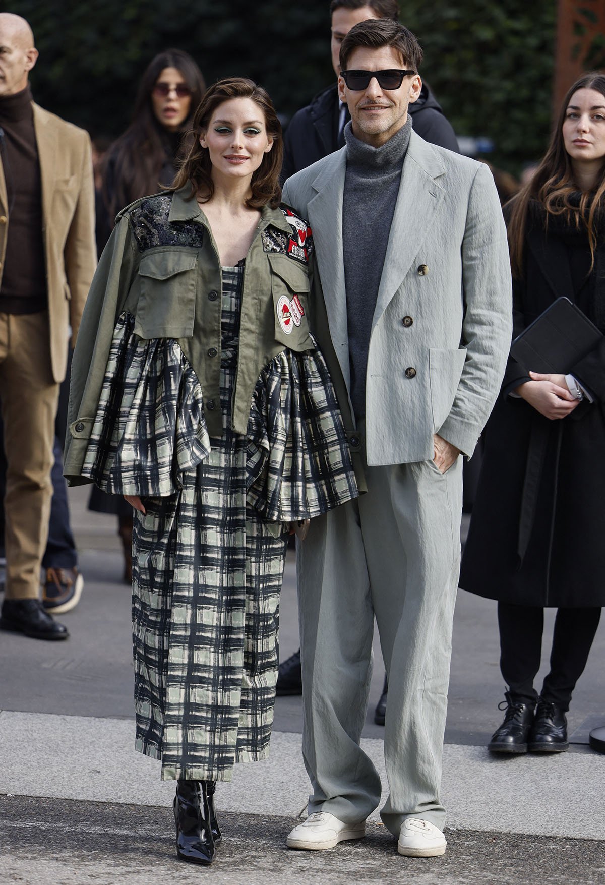 Olivia Palermo, with her husband Johannes Huebl, layers her midi dress with a matching plaid jacket featuring khaki trims that enhance the look's ruggedness